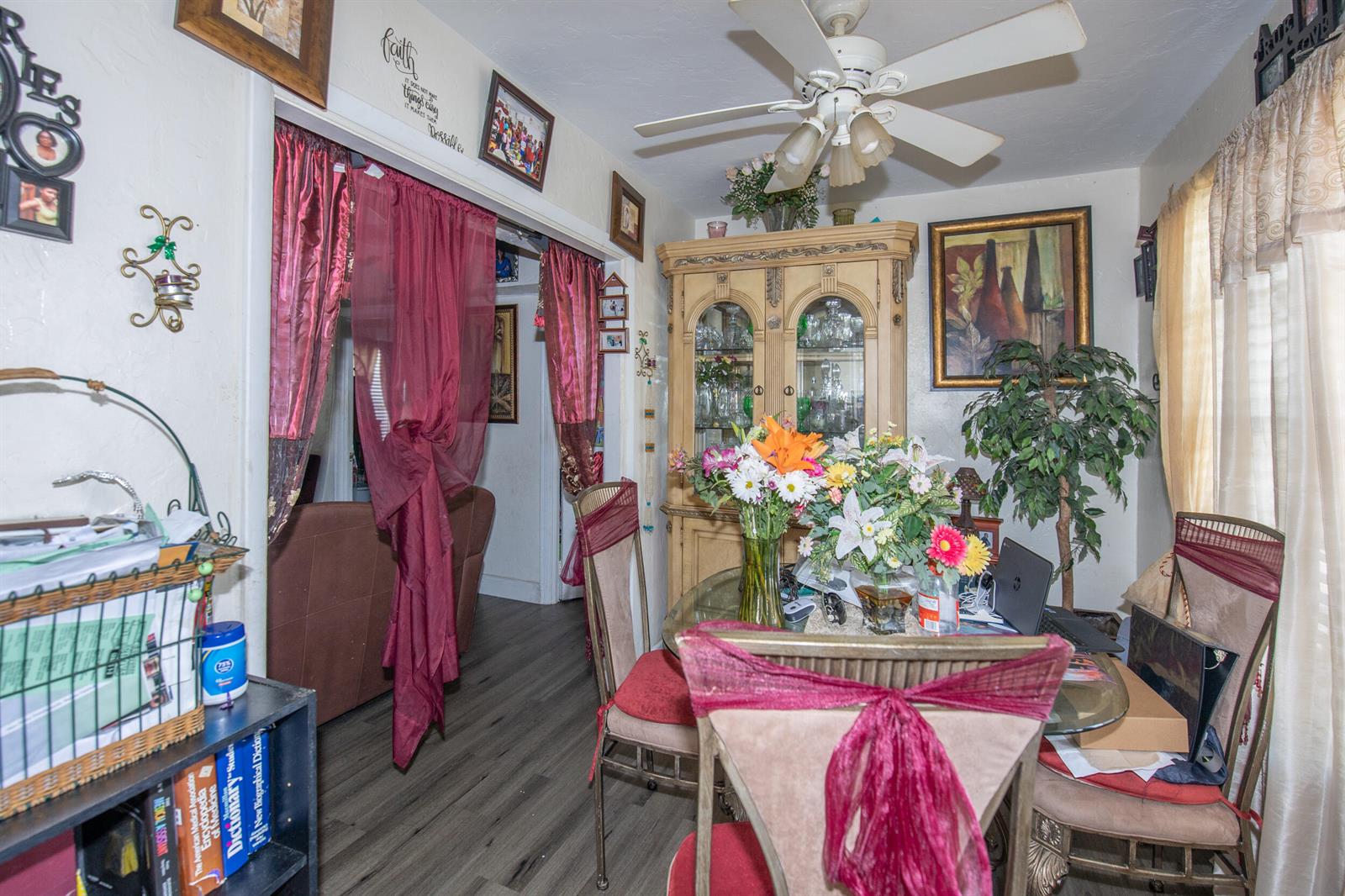 A dining room features a glass table, floral centerpieces, a china cabinet, and red curtains — 922/928 S Dixie Highway, FL 33460, FL