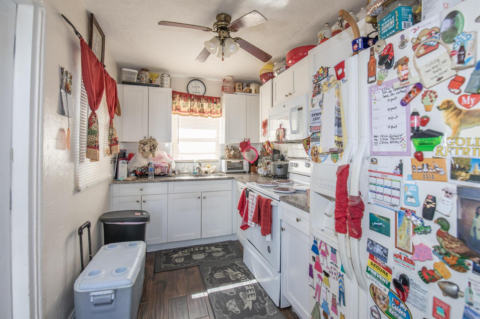 A small kitchen features white cabinets, a ceiling fan, and a refrigerator covered in magnets — 922/928 S Dixie Highway, FL 33460, FL