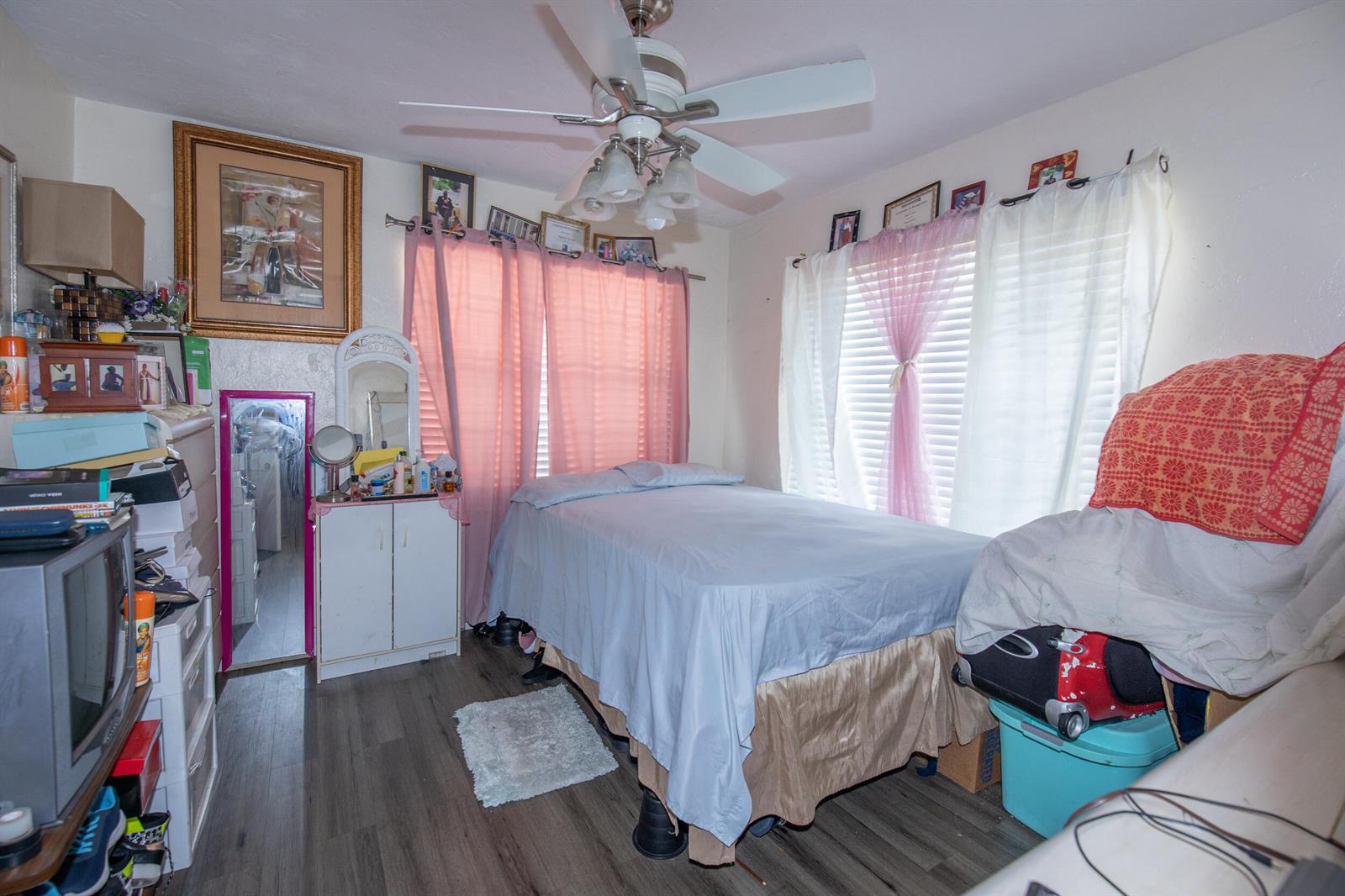 A bedroom features a bed with light blue bedding, pink curtains, and a ceiling fan — 922/928 S Dixie Highway, FL 33460, FL