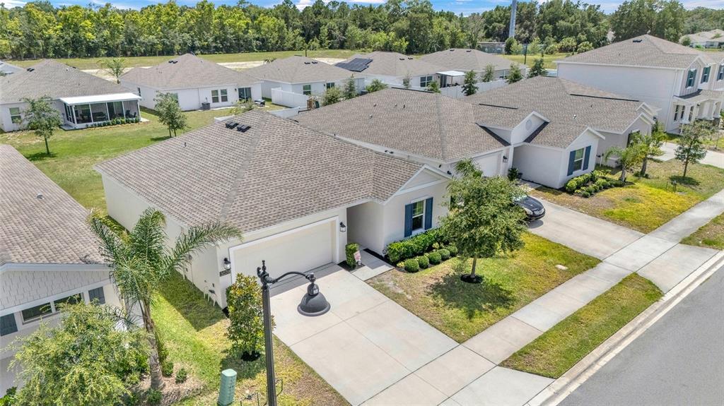 An aerial view shows several suburban houses with beige stucco walls and gray shingled roofs — 3078 BLUE BONNET LANE, OSTEEN, FL