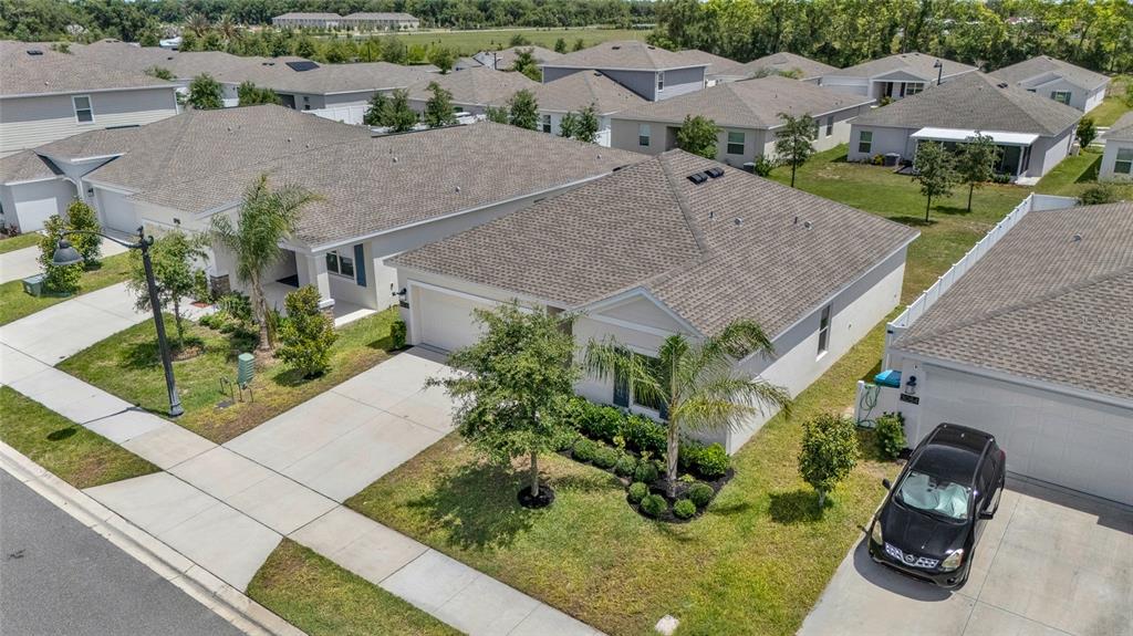 An aerial view shows suburban houses with shingled roofs, driveways, and small landscaped front yards — 3078 BLUE BONNET LANE, OSTEEN, FL