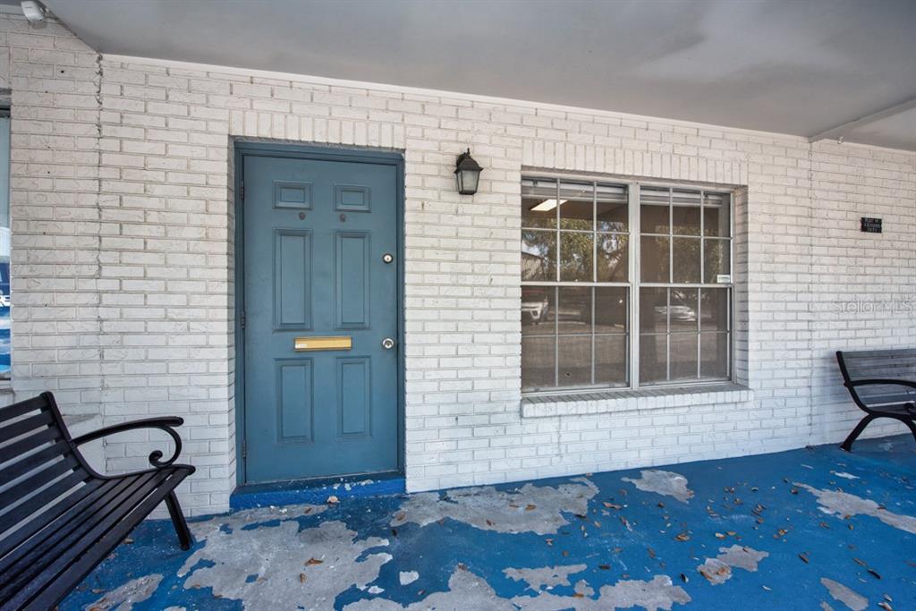A blue door and a window are set into a white brick wall above a porch — 7410 COMMERCE STREET UNIT 101, RIVERVIEW, FL