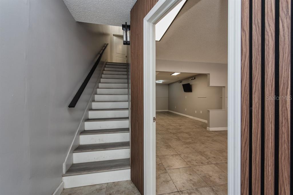 A staircase with gray and white steps leads upward next to a tiled room — 7410 COMMERCE STREET UNIT 101, RIVERVIEW, FL