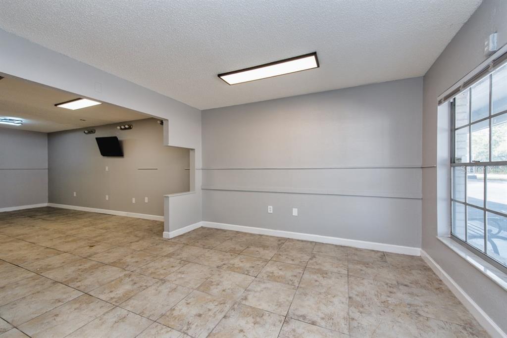 An empty room with light gray walls, tile flooring, and a large window — 7410 COMMERCE STREET UNIT 101, RIVERVIEW, FL
