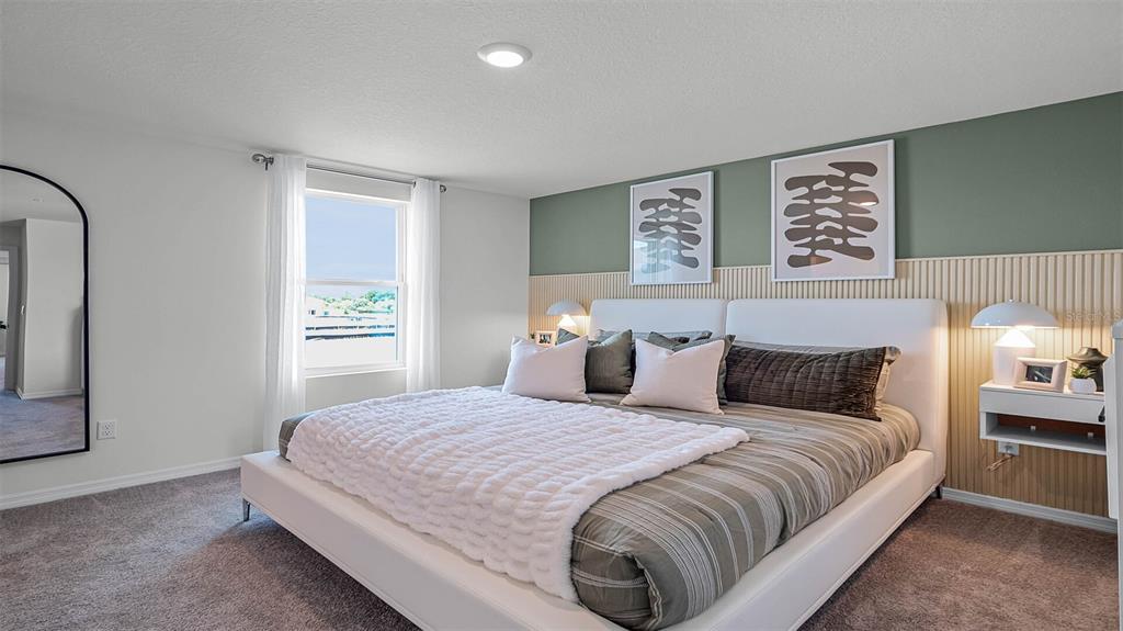 A bedroom features a white bed, a green accent wall, and vertical wood paneling — 16570 BARBOURS CREEK WAY, WINTER GARDEN, FL