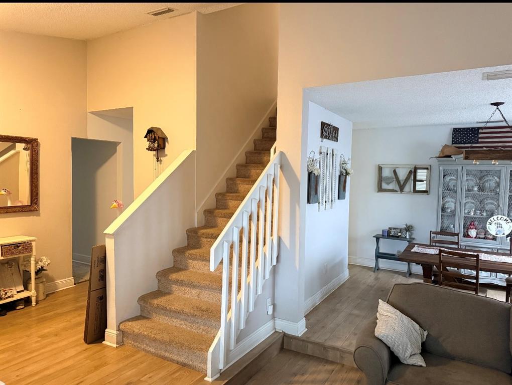 An interior view showing a carpeted staircase with white railings next to a dining area — 4303 ELLENVILLE PLACE, VALRICO, FL