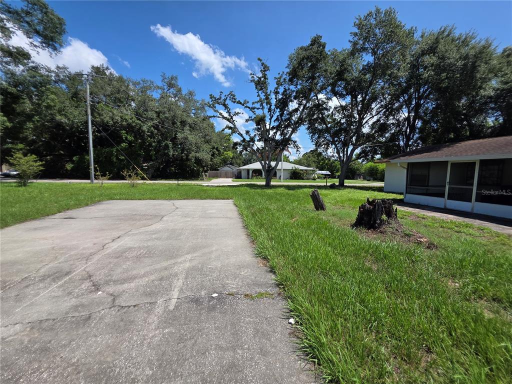 A concrete driveway leads to a grassy yard with two tree stumps and a house — 2312 7TH ST E, BRADENTON, FL