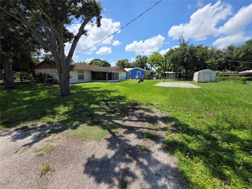 A backyard view of a house with a screened porch, a shed, and a concrete pad — 2312 7TH ST E, BRADENTON, FL
