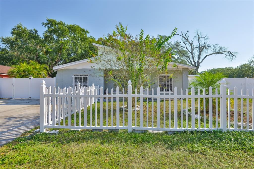 A single-story house with a white picket fence and security bars on the windows — 3901 N CLEARFIELD AVENUE, TAMPA, FL