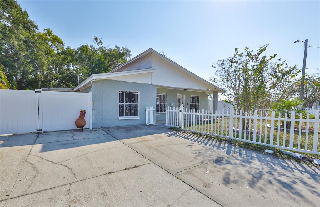 A single-story house with a light blue exterior, white fencing, and a concrete driveway — 3901 N CLEARFIELD AVENUE, TAMPA, FL