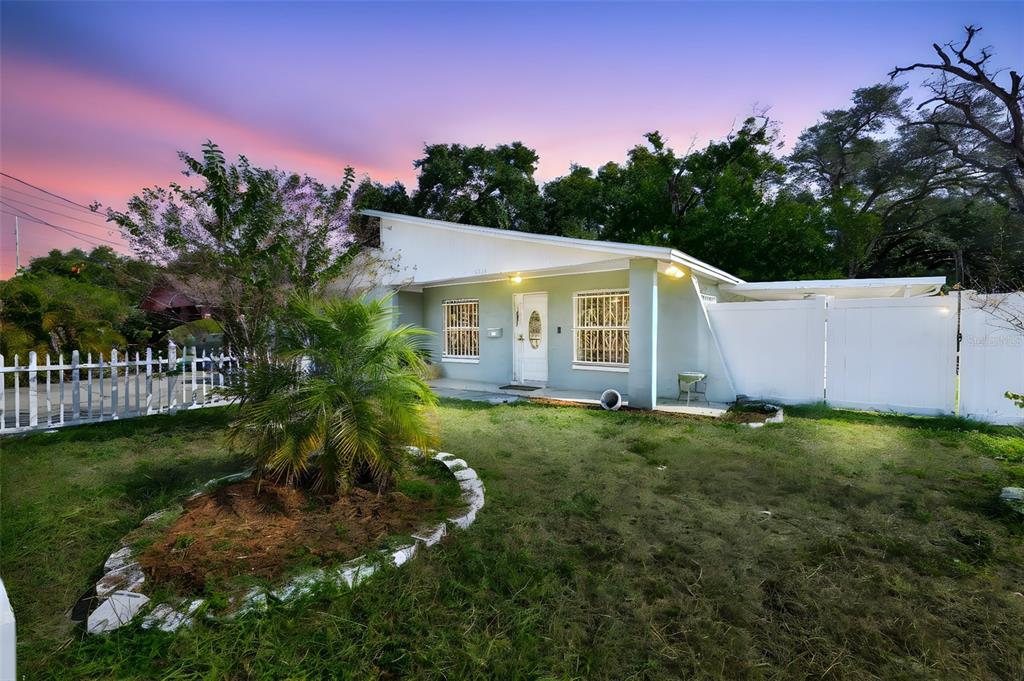 A single-story house with a light green exterior, a front porch, and a white fence — 3901 N CLEARFIELD AVENUE, TAMPA, FL