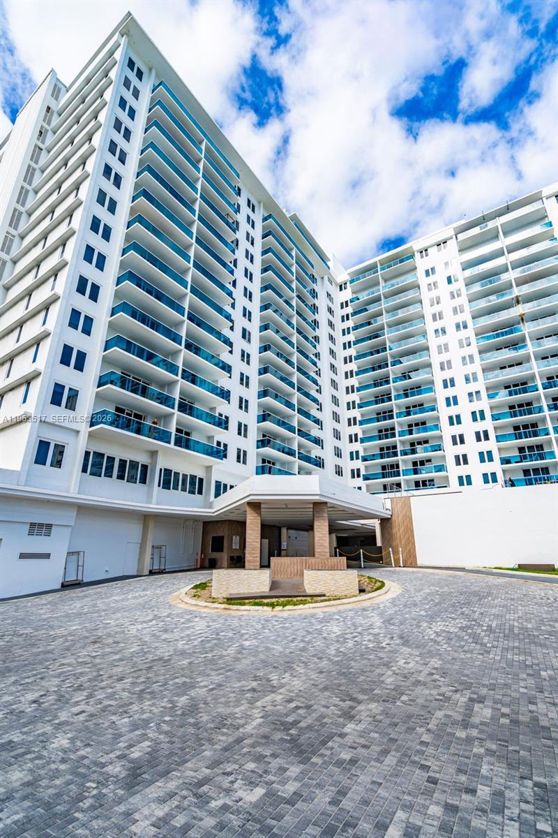 A low-angle exterior view of a modern high-rise apartment building with a paved driveway — 2301 Collins Ave # 621, Miami Beach FL 33139, MIAMI BEACH, FL