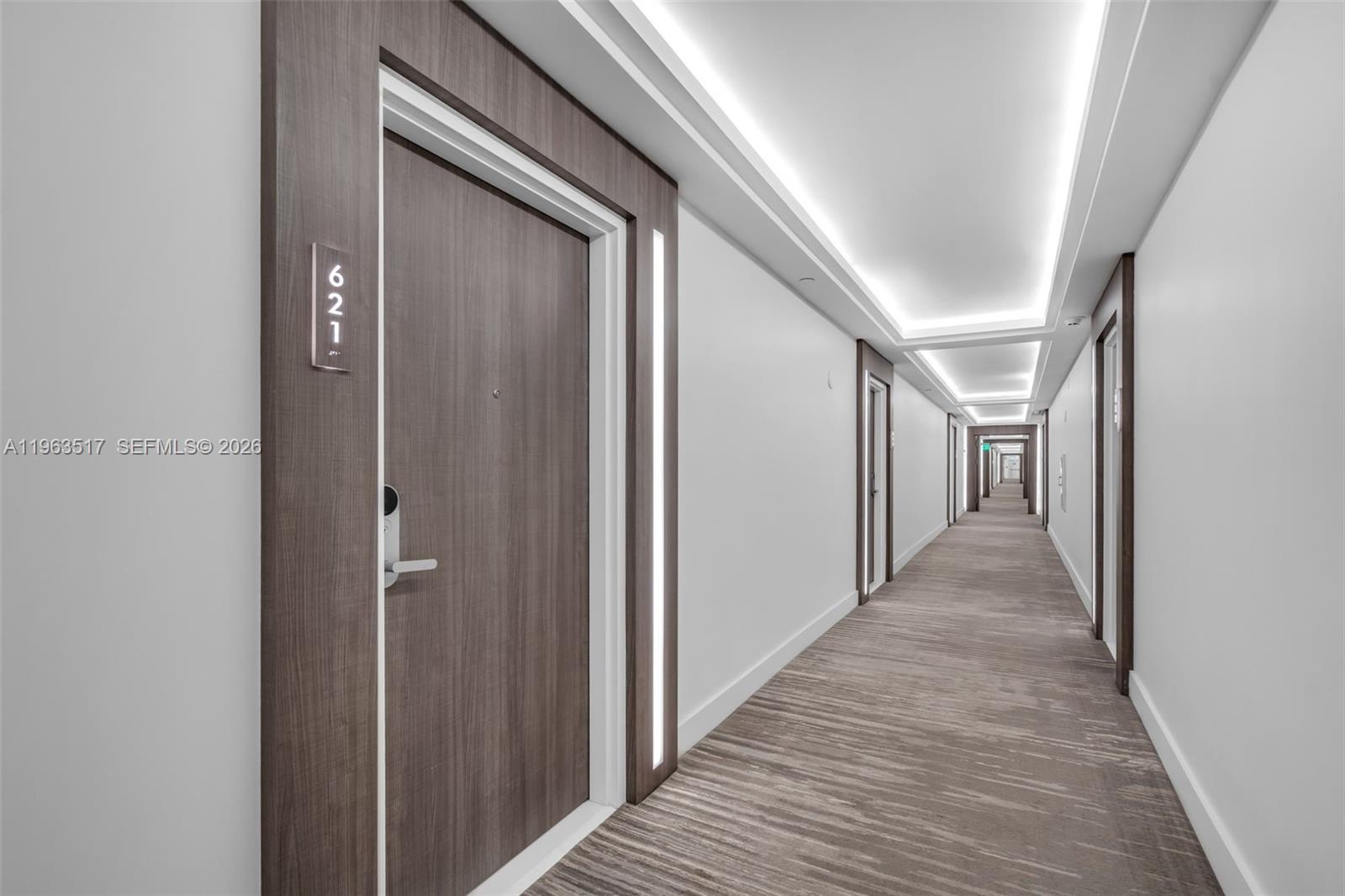 A long hallway features wood-paneled doors, recessed ceiling lighting, and patterned carpet flooring — 2301 Collins Ave # 621, Miami Beach FL 33139, MIAMI BEACH, FL