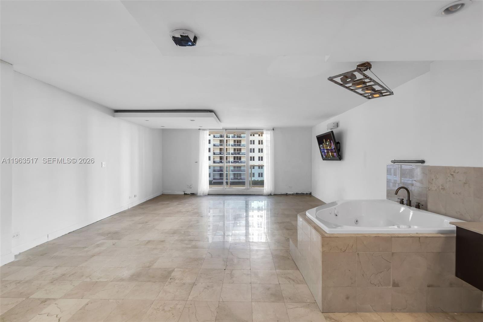 A spacious room features light tile flooring, a built-in jetted tub, and a wall-mounted television — 2301 Collins Ave # 621, Miami Beach FL 33139, MIAMI BEACH, FL