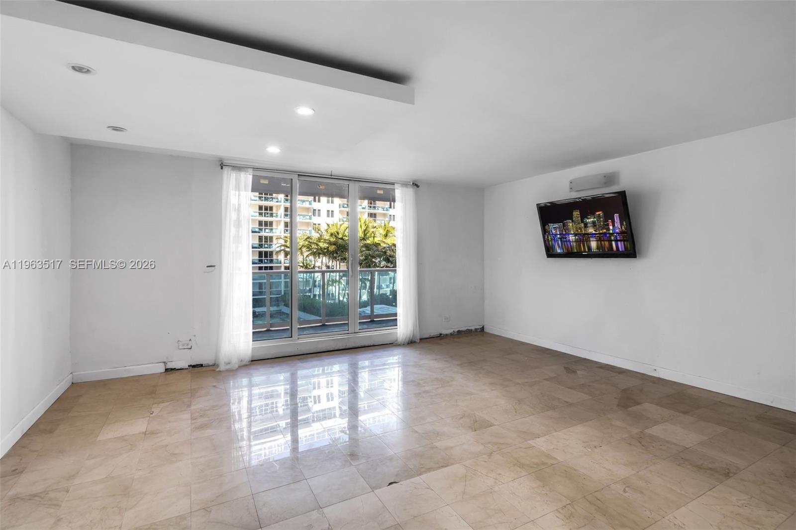 An empty living room features beige tile flooring, white walls, and a sliding glass door — 2301 Collins Ave # 621, Miami Beach FL 33139, MIAMI BEACH, FL