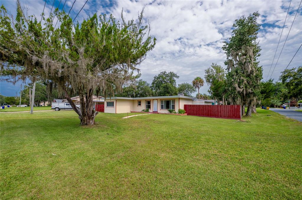 A single-story house with a light-colored exterior and a red fence sits on a lawn — 1101 16TH STREET, EDGEWATER, FL