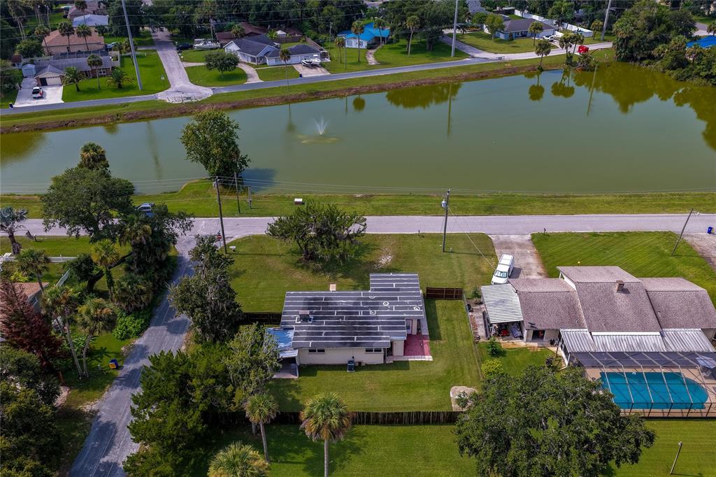 An aerial view shows a house with a pool next to a lake and road — 1101 16TH STREET, EDGEWATER, FL
