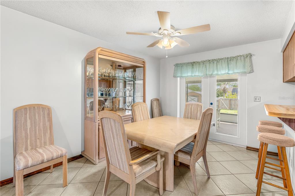 A dining room features a light wood table, matching chairs, a china cabinet, and tile flooring — 2970 LAGOON AVENUE, DELTONA, FL
