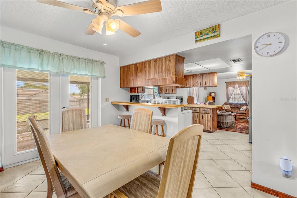 A dining area with a wooden table and chairs opens to a kitchen with wood cabinets — 2970 LAGOON AVENUE, DELTONA, FL