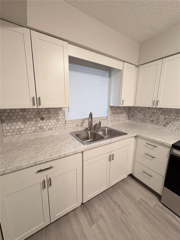 A kitchen features white cabinets, marble-look countertops, a hexagonal tile backsplash, and light wood flooring — 434 AVENUE D SE, WINTER HAVEN, FL