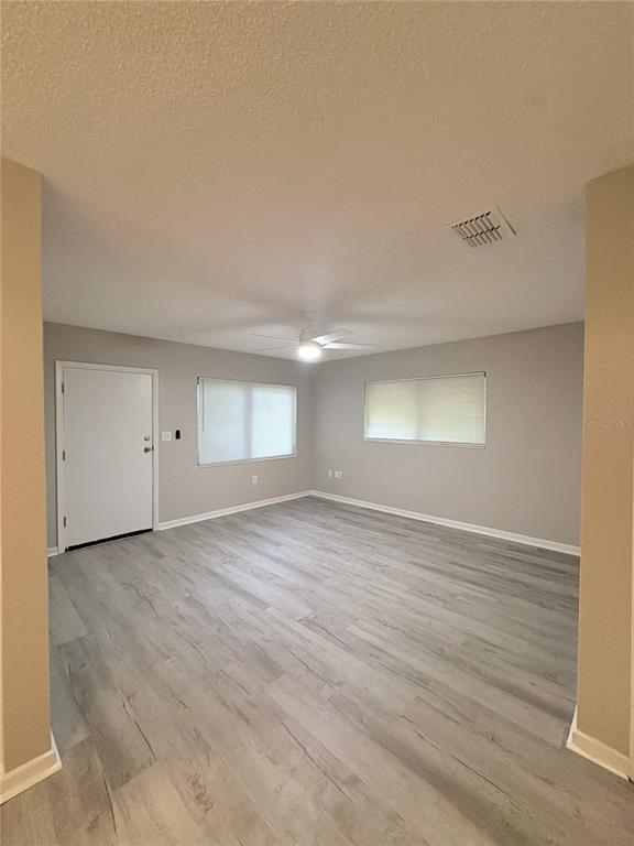 An empty room features light gray wood-look flooring, neutral walls, and a ceiling fan — 434 AVENUE D SE, WINTER HAVEN, FL