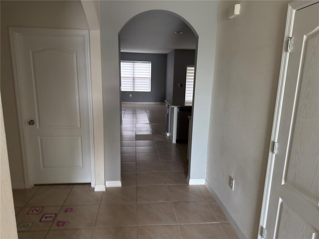 An entryway with tile flooring leads through an arched doorway into an open living area — 1973 CARNOSTIE ROAD, WINTER HAVEN, FL