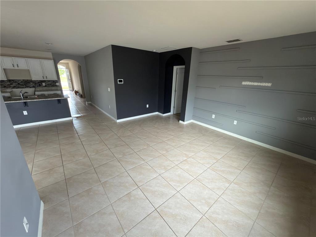 An open-concept living area features tile flooring, a kitchen island, and a gray accent wall — 1973 CARNOSTIE ROAD, WINTER HAVEN, FL
