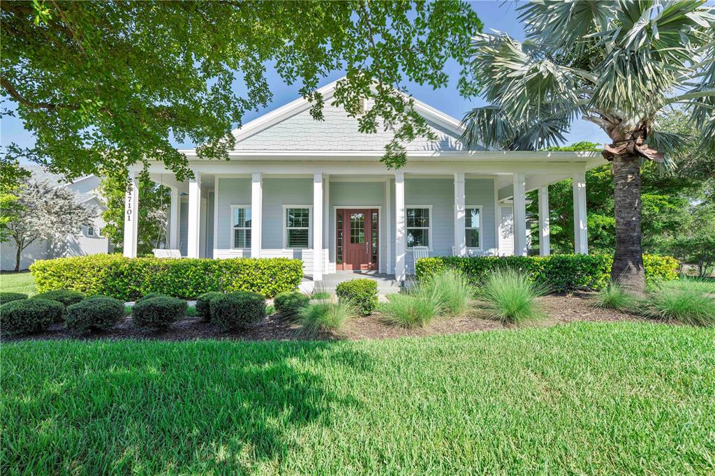 A light blue house with a covered front porch, white columns, and a landscaped yard — 17101 BULLHORN CIRCLE, PUNTA GORDA, FL