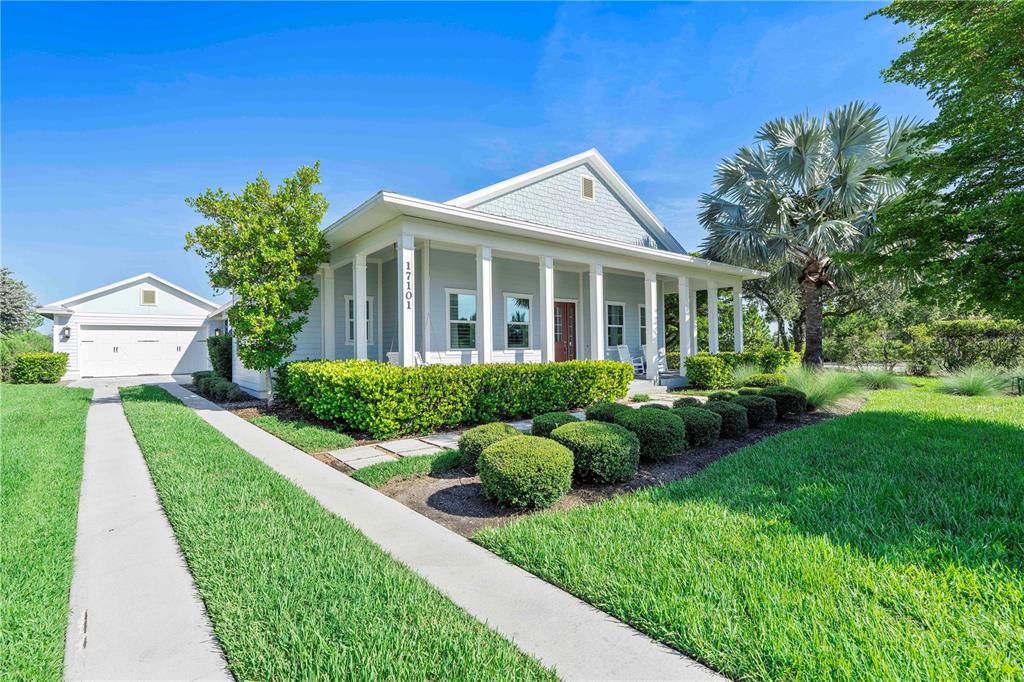A light blue house with a front porch and a detached garage sits on a lawn — 17101 BULLHORN CIRCLE, PUNTA GORDA, FL