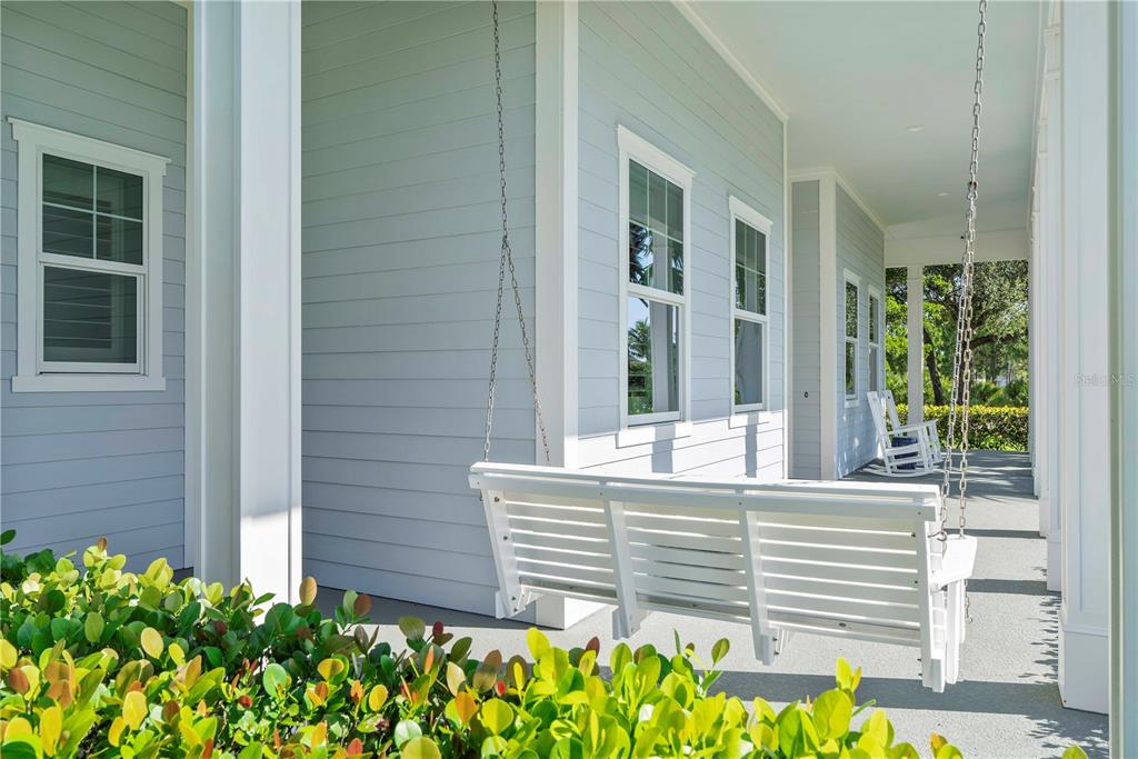 A white porch swing hangs on a covered patio with light blue siding and windows — 17101 BULLHORN CIRCLE, PUNTA GORDA, FL