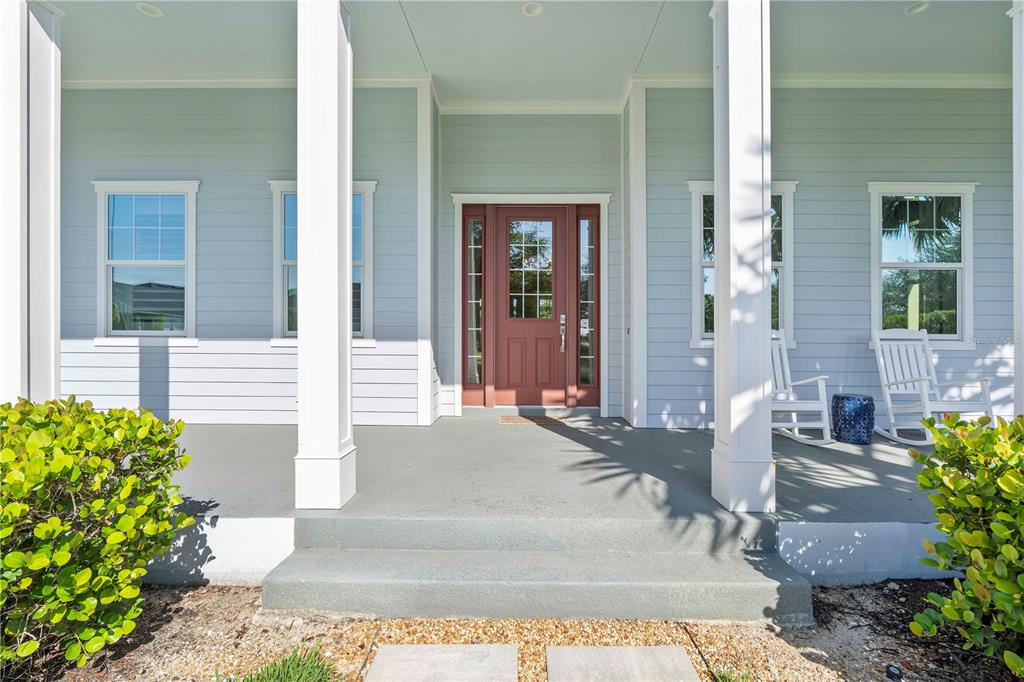 A front porch with light blue siding, white columns, and a red front door — 17101 BULLHORN CIRCLE, PUNTA GORDA, FL