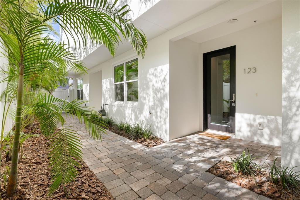 A paved walkway leads to the front entrance of a modern white house with palm trees — 123 5TH AVENUE N, ST PETERSBURG, FL