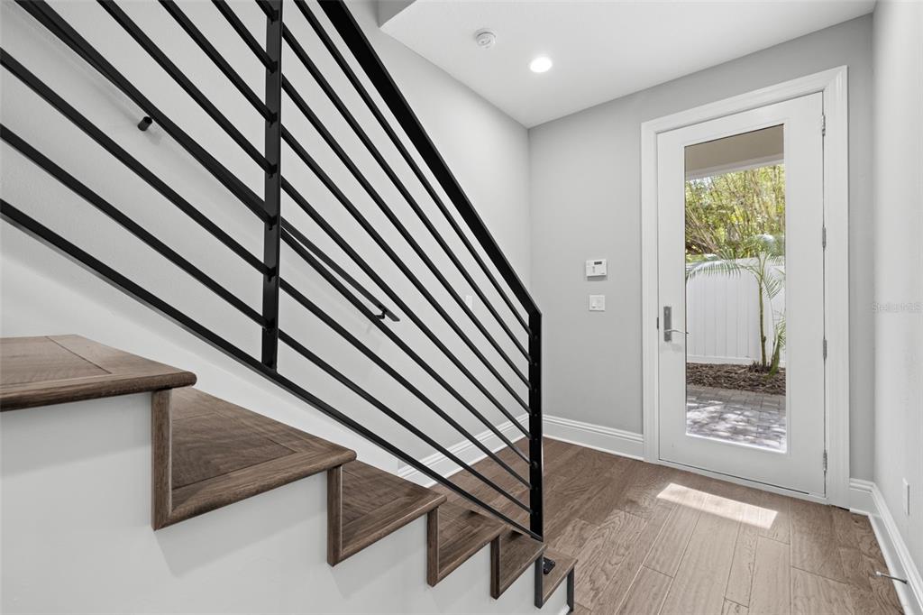 A modern staircase with black metal railings leads down to a foyer with wood flooring — 123 5TH AVENUE N, ST PETERSBURG, FL