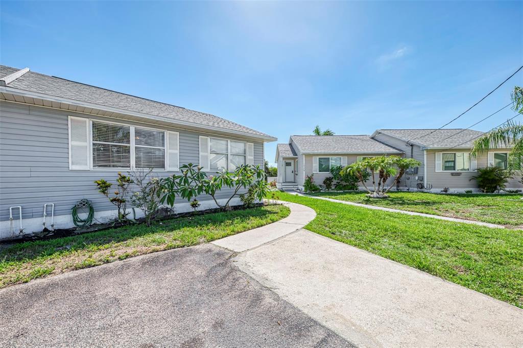 A concrete walkway leads between two single-story houses with gray siding and shingled roofs — 14300 WORTHWHILE ROAD, PORT CHARLOTTE, FL