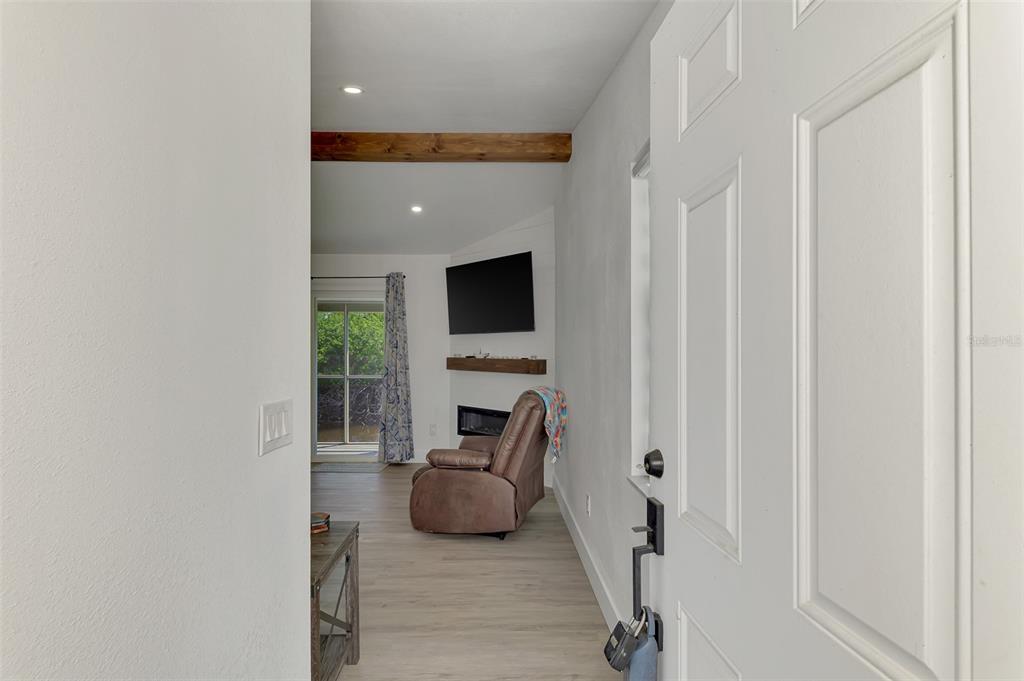 An entryway leads into a living area with a fireplace, television, and sliding glass doors — 14300 WORTHWHILE ROAD, PORT CHARLOTTE, FL