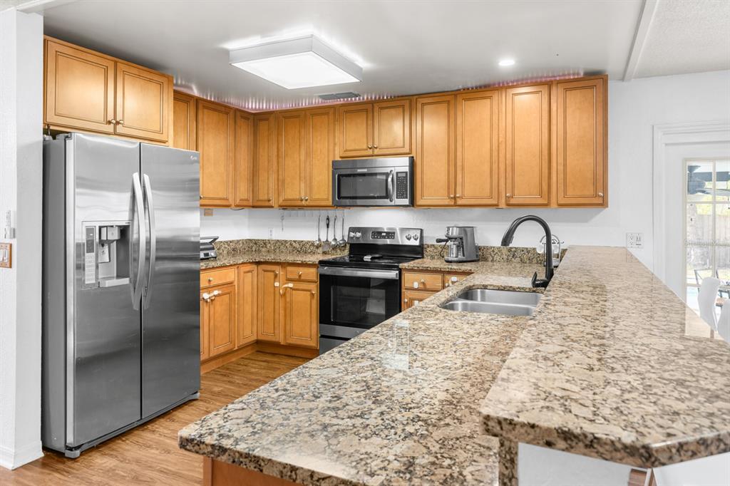 A kitchen with wood cabinets, granite countertops, stainless steel appliances, and a breakfast bar — 8243 PAMLICO STREET, ORLANDO, FL