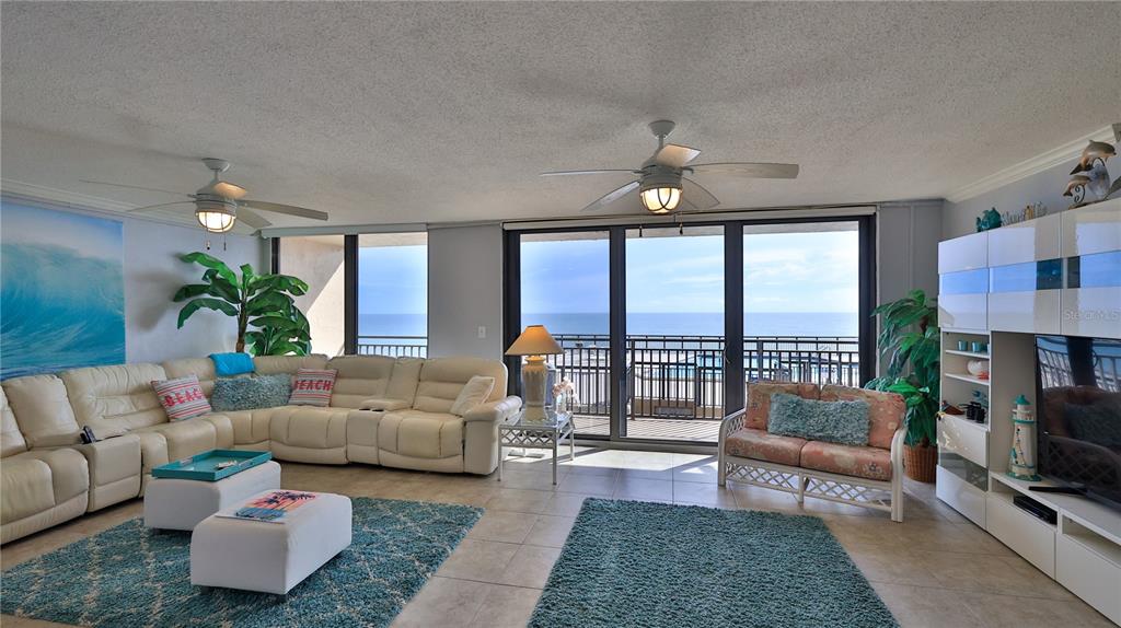 A living room features a large white sectional, two ceiling fans, and a balcony view — 4139 S ATLANTIC AVENUE UNIT B204, NEW SMYRNA BEACH, FL