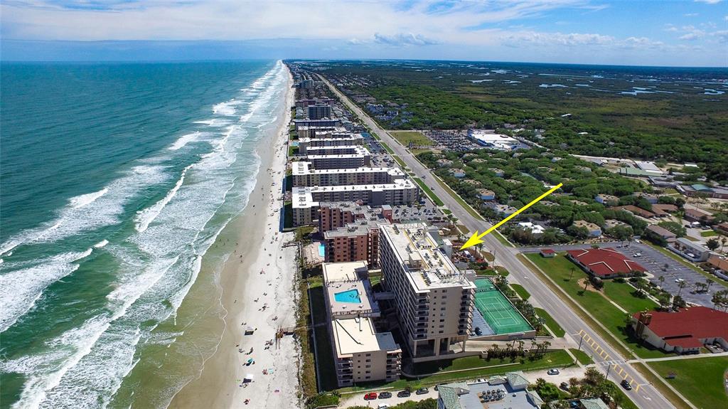 An aerial view of a beachfront high-rise condominium complex with a tennis court and pool — 4139 S ATLANTIC AVENUE UNIT B204, NEW SMYRNA BEACH, FL