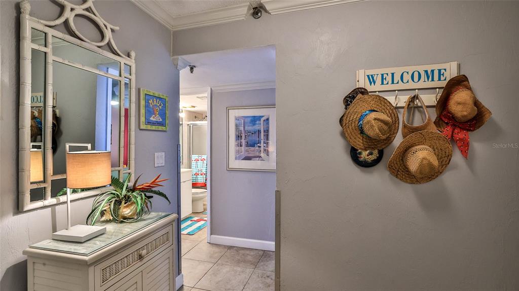 An entryway features a bamboo-framed mirror, a console table, and a wall-mounted welcome hat rack — 4139 S ATLANTIC AVENUE UNIT B204, NEW SMYRNA BEACH, FL