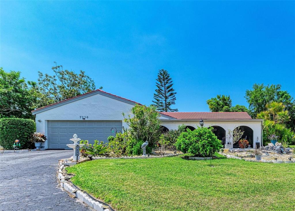 A single-story house with a white exterior, a two-car garage, and a landscaped front yard — 7236 LAS CASAS DR, SARASOTA, FL