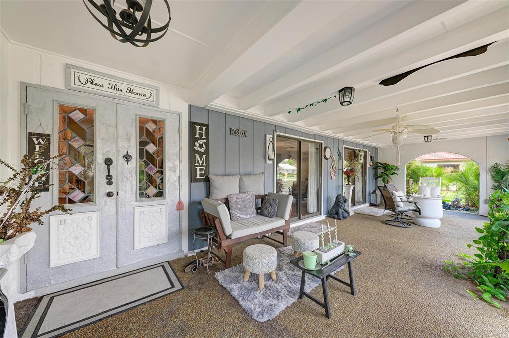 A covered patio features a gray double door, outdoor seating, and a concrete floor — 7236 LAS CASAS DR, SARASOTA, FL