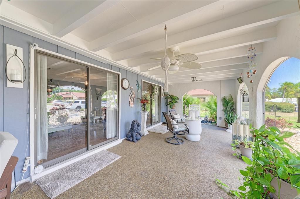 A covered patio features a textured floor, sliding glass doors, and a ceiling fan — 7236 LAS CASAS DR, SARASOTA, FL