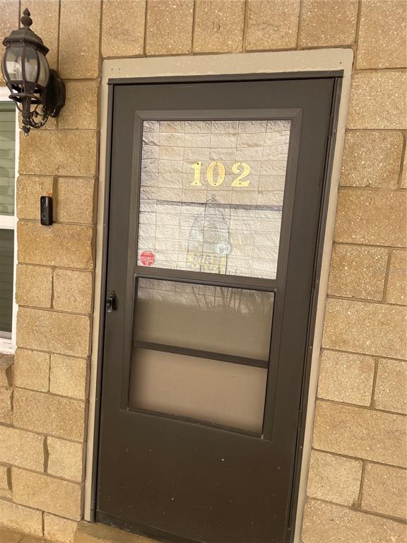 A brown storm door with the number 102 is set into a tan stone wall — 2837 NE 3RD STREET UNIT 102, OCALA, FL