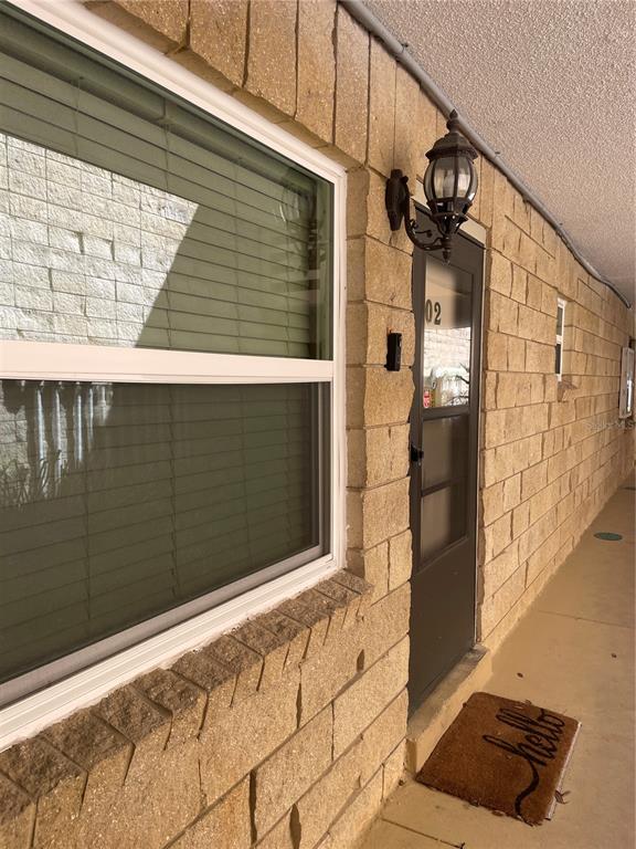 A view of a building exterior featuring a brick wall, a window, and a door — 2837 NE 3RD STREET UNIT 102, OCALA, FL