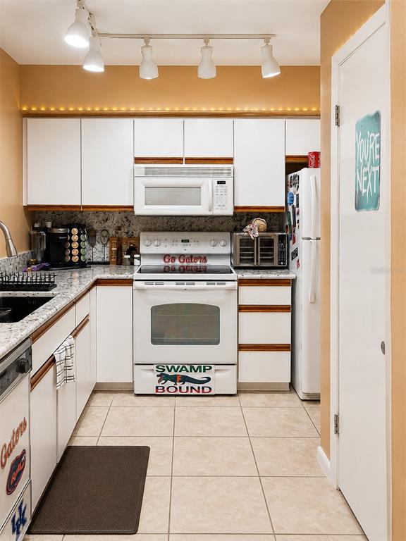 A kitchen features white cabinets, granite countertops, a white stove, and a track lighting fixture — 2837 NE 3RD STREET UNIT 102, OCALA, FL