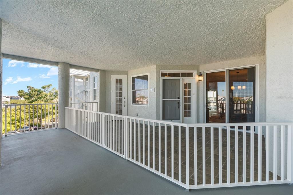 A covered balcony features a white railing, tile flooring, and glass sliding doors — 1240 DOLPHIN BAY WAY UNIT 401, SARASOTA, FL