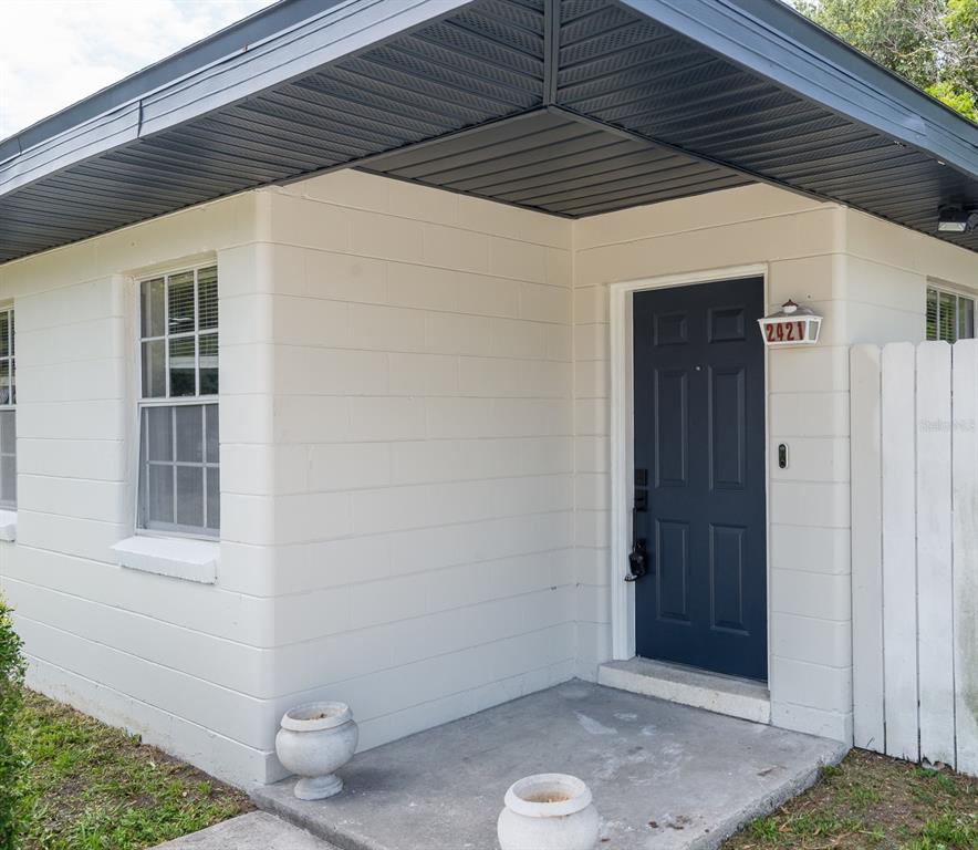 A concrete block house exterior features a dark blue front door and a covered porch — 2421 LINSEY STREET, TAMPA, FL
