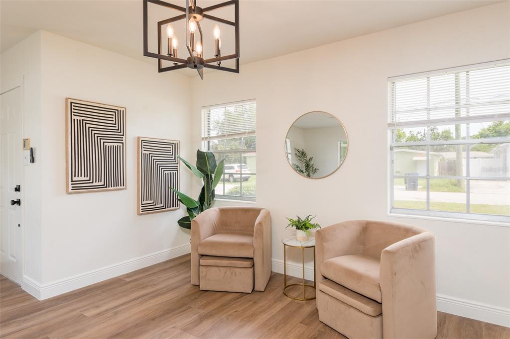 A bright room features two tan armchairs, a small side table, and modern wall art — 2421 LINSEY STREET, TAMPA, FL