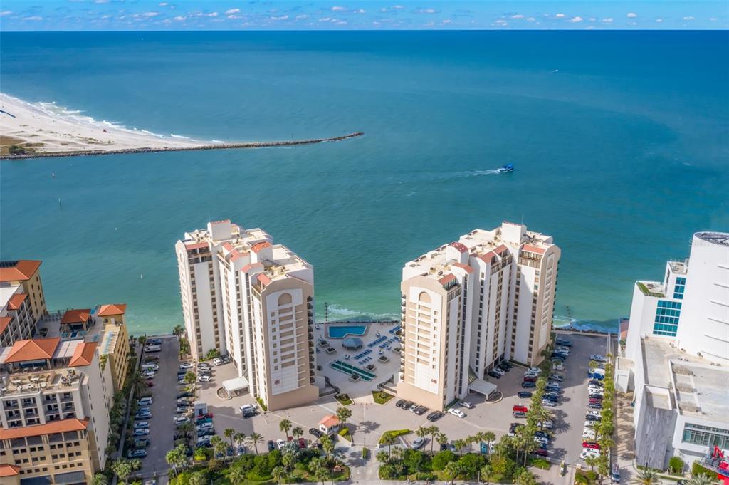 An aerial view shows two high-rise residential buildings situated along a sandy beach and ocean — 440 S GULFVIEW BOULEVARD UNIT 1701, CLEARWATER BEACH, FL