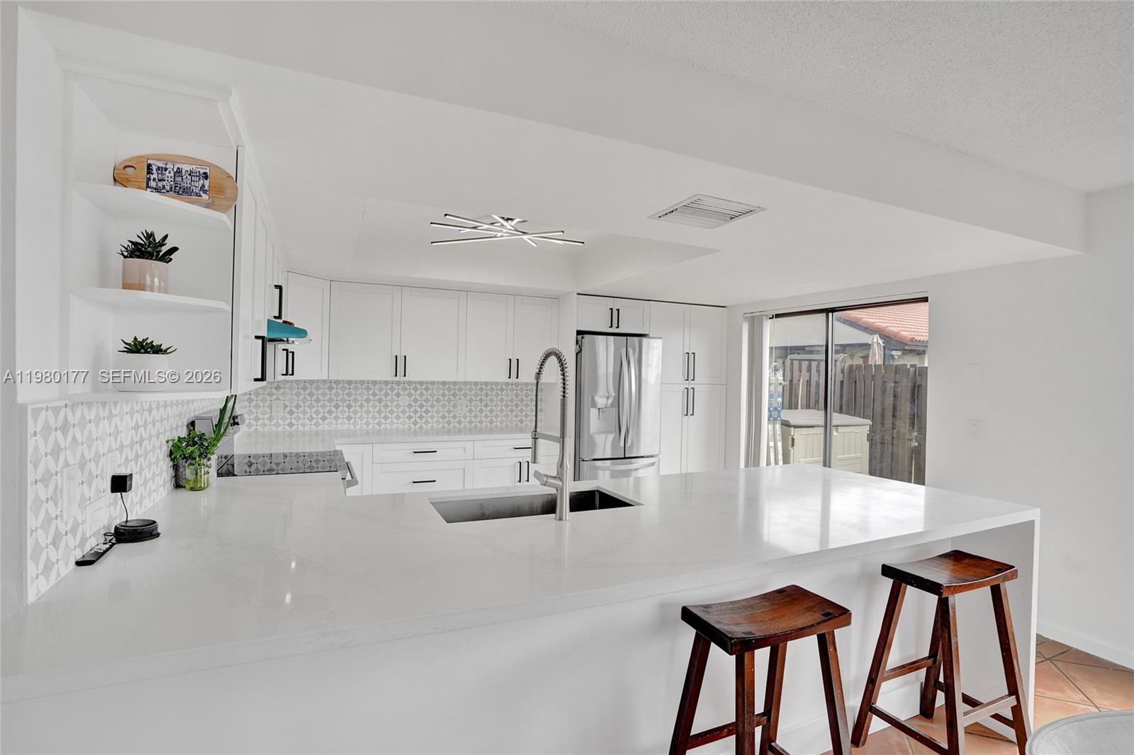 A modern white kitchen features a quartz island, stainless steel appliances, and patterned tile backsplash — 15292 SW 46th Ln Br # 64, Miami FL 33185, MIAMI, FL
